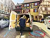 France - Sep 22, 2022: Caucasian female postal worker courier sorting parcels from delivery La Poste French operator van in Alsatian village