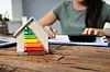 A view of a DPE rating on a model house, with someone working on a calculator in the background