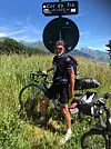 Man with bike standing under Col du Tra sign