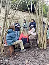Image shows students at a forest school outdoors learning with teachers.