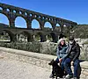 View of Keith Van Sickle, wife Val and dog Mica sitting in front of a viaduct in Provence