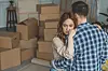 Couple,Hugging,At,New,Apartment,Full,Of,Cardboard,Boxes,,Moving