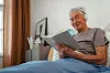 Senior,Man,Relaxing,In,His,Bed,,Learning,Book,And,Listening