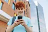 Cheerful,Red-haired,Teenage,Boy,Standing,Outside,A,Modern,Building,,Smiling