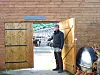 A man stands beside an open greenhouse door