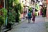 An elderly couple walking through a cobbled street in France