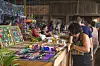 People browsing colourful Hmong handicraft stalls inside a covered market in Cacao.