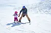 Father teaching his young daughter to ski