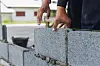 Worker's hands placing bricks to build a wall