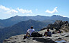 Couple sitting on precipice looking over mountains