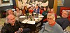 Group seated around a restaurant table with drinks and papers during a meeting