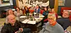 Group seated around a restaurant table with drinks and papers during a meeting