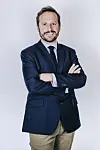 Business professional in navy suit standing with folded arms in studio.