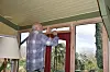 Man measuring a wooden frame above a red door inside a conservatory