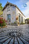 Mosaic-decorated house at Picassiette with patterned tiled courtyard and flowers.