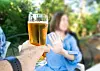 Woman outdoors raising her hand to refuse a glass of beer offered in the foreground