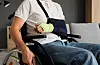 Young man with arm cast in sling sitting in a wheelchair indoors