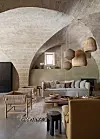 Stone-vaulted living room with neutral sofas, woven chairs and pendant lights