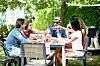 Group of friends raising drinks at a picnic table in a sunny garden