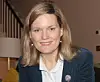 Smiling woman in a blazer seated in a living room. Mary Harrod, professor of French and screen studies at the University of Warwick, England