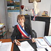 Official wearing a tricolour sash signing papers at a desk in an office