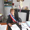 Official wearing a tricolour sash signing papers at a desk in an office
