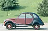 Vintage Citroën 2CV car parked on a roadside with grass and trees behind