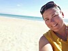 Smiling person taking a selfie on a sunny sandy beach by the sea