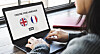 Hands using a laptop with a language choice screen showing British and French flags.