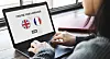 Hands using a laptop with a language choice screen showing British and French flags.