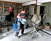 Worker pouring material into a cement mixer in a rustic workshop.