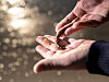Close-up of hands holding a small lugworm over a blurred body of water.