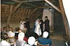 Wedding guests seated in a rustic hall watching a ceremony at the front of the room.