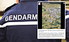 Close-up of a gendarmerie uniform beside a handheld screen showing an aerial map and text.