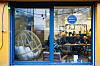 View through a window into Bistrot Bertha, showing tables, seated customers and a hanging chair.