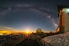 Sunrise over a domed observatory with snow-covered walkways and a starry sky.