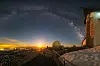 Sunrise over a domed observatory with snow-covered walkways and a starry sky.