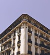 Ornate corner building with balconies and decorative façade against a lavender sky in Nice, France.