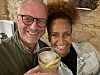 Two smiling adults holding drinks in a rustic indoor setting.