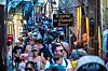 Crowded narrow street in Mont-Saint-Michel with tourists, shops and a Creperie Du Chapeau Rouge sign.