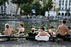 People sitting and swimming along the Canal Saint-Martin in Paris during a heatwave.