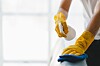 Gloved hands wiping and spraying disinfectant on a surface.