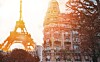 Parisian building with balconies in warm light, Eiffel Tower in the background.