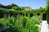 Formal garden in Yvoire, France, with hedges, flowering plants and a gravel path under a clear blue sky.