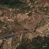 Aerial view of a large city with roads, hills and a reservoir.