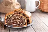 Slices of homemade chocolate and vanilla marble cake on a plate on a wooden table.