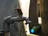 Metal tap dripping water with a blurred background.