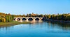 Pont Neuf spanning the Garonne River in Toulouse with trees and a clear blue sky.