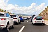 Cars lined up in heavy traffic on a highway under a cloudy sky.