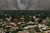 Smoke rises behind houses and trees in Lege-Cap-Ferret, Gironde, France.